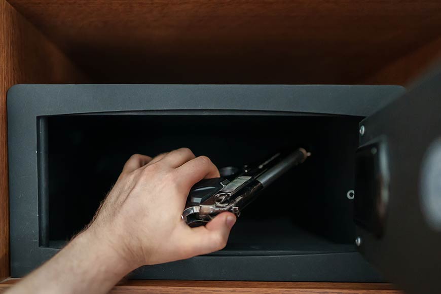 Photo of a person placing a handgun in a safe